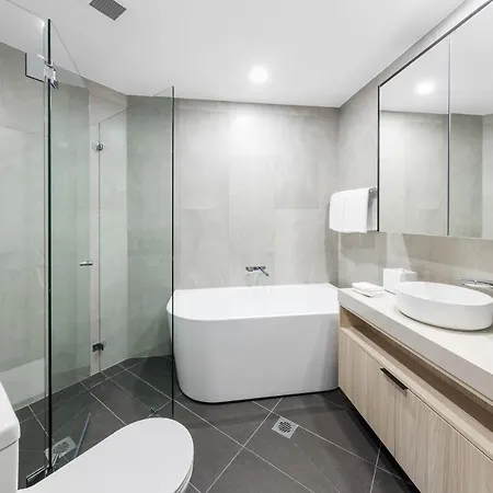 Meriton Suites Bondi Junction Sydney Exterior photo The photo shows a modern bathroom featuring a sleek design. It includes a glass-enclosed shower area with a rainfall showerhead, a freestanding bathtub, and a double sink vanity with storage underneath. The walls are finished with neutral tiles, and 