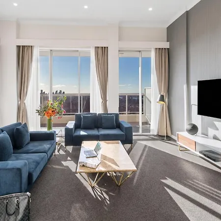 Meriton Suites Bondi Junction Sydney Exterior photo The photo depicts a modern living room with a stylish and contemporary design. It features a cozy seating arrangement with a blue sofa and two matching armchairs. In front of the seating area is a coffee table with a geometric design. The room has la