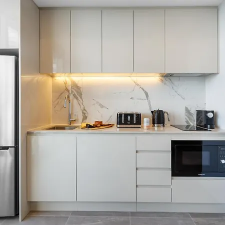 Meriton Suites Bondi Junction Sydney Exterior photo The photo shows a modern kitchen featuring a sleek design. It includes light-colored cabinetry with a smooth finish and upper cabinets that blend seamlessly with the wall. The countertop is made of a light stone, complementing the overall aesthetic. 